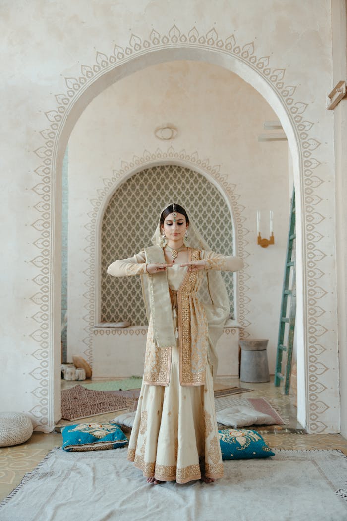 Woman in traditional Indian attire performing a classical dance indoors.